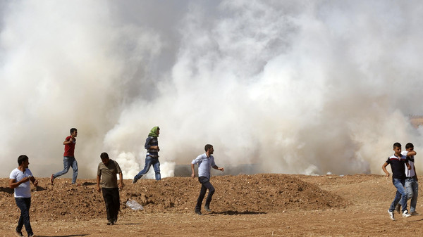 Protesters run away from tear gas during a pro-Kurdish demonstration, near the Mursitpinar border crossing on the Turkish-Syrian border, in Suruc