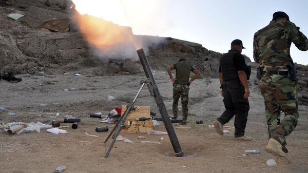 Members of Iraqi security forces and Shiite fighters fire a mortar during clashes with militants of the Islamic State, in Diyala province north of Baghdad