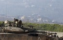 Israeli soldiers stand atop a tank near the border with Lebanon