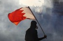 A protester carries a Bahraini flag as they clash with riot police in the village of Bilad Al Qadeem south of Manama