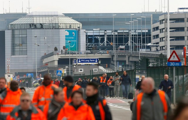People leave the scene of explosions at Zaventem airport near Brussels, Belgium