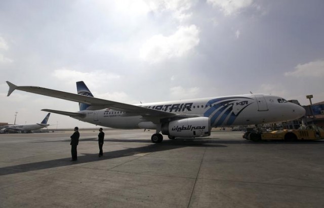 Airport staff stand next to an EgyptAir plane on the runway at Cairo Airport