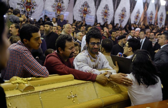 Relatives of victims react next to coffins arriving to the Coptic church that was bombed on Sunday in Tanta