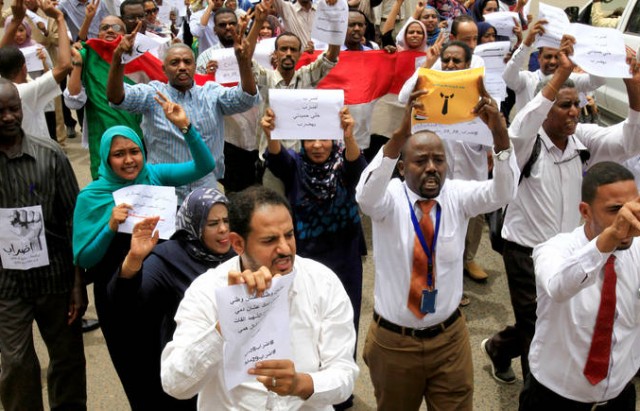 Members of Sudanese alliance of opposition and protest groups chant slogans outside an office block during the first day of a strike, as tensions mounted with the country's military rulers over the transition to democracy in Khartoum